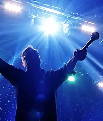 Bernard Sumner from New Order pointing the microphone into the camera during mutli-camera pay-per-view livestream at the O2 Arena in London.